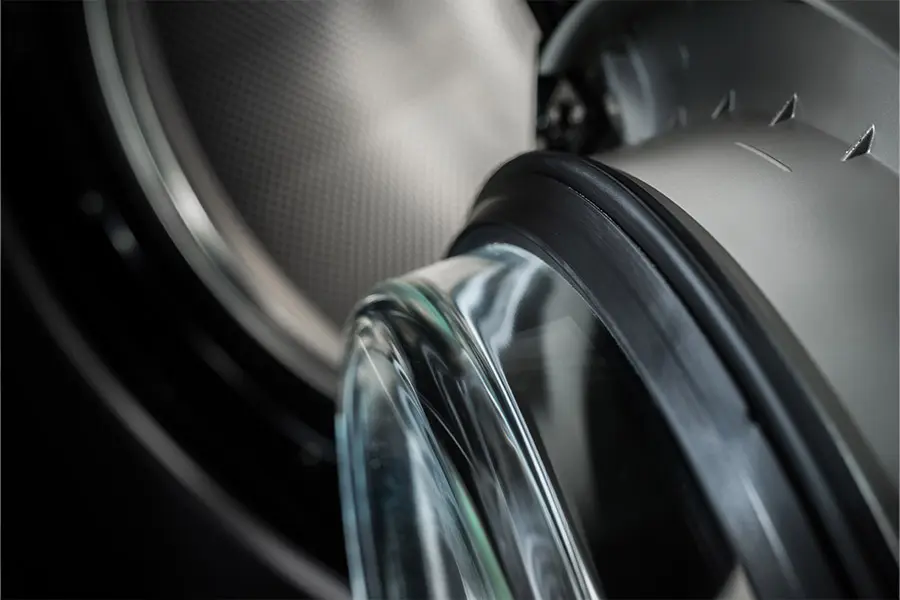 Close-up van een open wasmachinedeur met rubberen rand en trommel op de achtergrond
